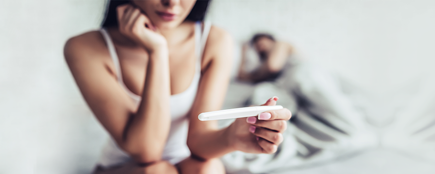 Woman looking at a pregnancy with her partner in the background