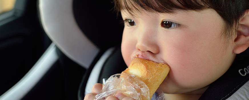 Baby Eating Bread in a Car Seat While Traveling