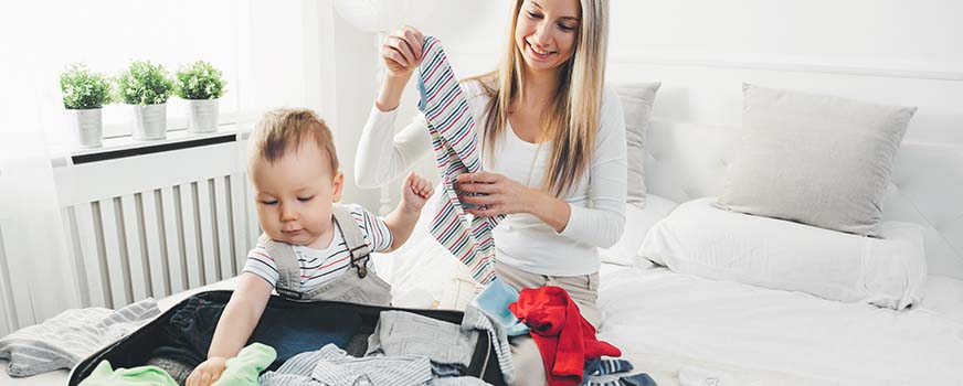 Baby Helping Mom Pack Clothes in a Suitcase