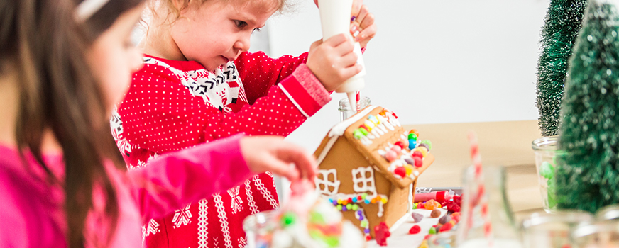 Crianças decorando casinhas de gengibre para as festas de fim de ano