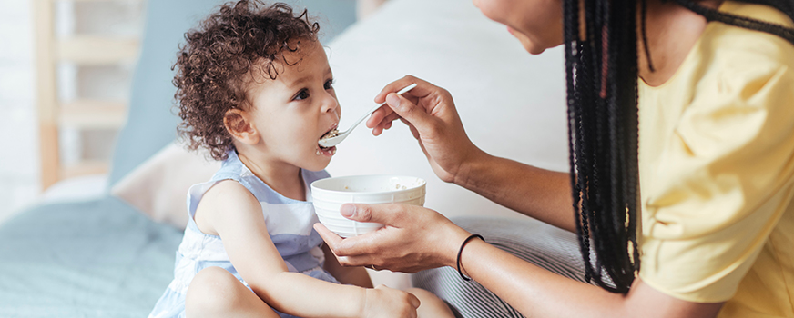 Mãe alimentando bebês com novos alimentos