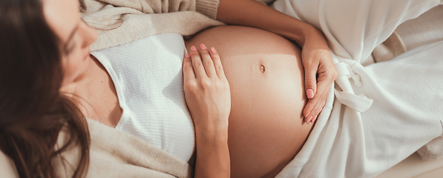 Mulher grávida segurando a barriga após fertilização in vitro